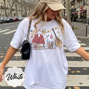 Pode incluir: Uma t-shirt branca com uma estampa gr&aacute;fica de um cardig&atilde; vermelho paisley, um chap&eacute;u de cowboy castanho, uma estrela de xerife com a etiqueta Sheriff Taylor, um microfone, uma guitarra ac&uacute;stica castanha, botas e blocos com TOY STORY.
