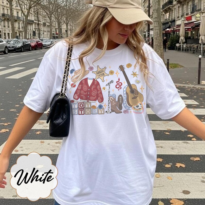 Pode incluir: Uma t-shirt branca com uma estampa gr&aacute;fica de um cardig&atilde; vermelho paisley, um chap&eacute;u de cowboy castanho, uma estrela de xerife com a etiqueta Sheriff Taylor, um microfone, uma guitarra ac&uacute;stica castanha, botas e blocos com TOY STORY.
