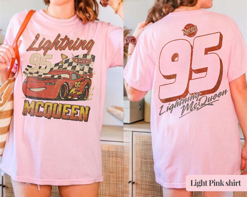 Puede incluir: Camiseta rosa claro con un dise&ntilde;o de Rayo McQueen de la pel&iacute;cula Cars. El dise&ntilde;o frontal incluye el n&uacute;mero 95, una bandera a cuadros y el texto "Lightning McQueen". La parte trasera de la camiseta muestra un gran n&uacute;mero 95 y el texto "Lightning McQueen".