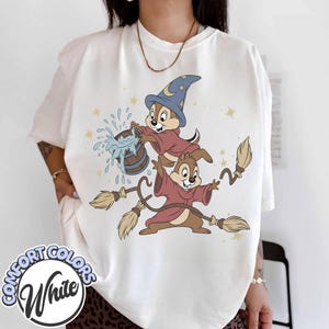 Könnte beinhalten: Weißes T-Shirt mit einer Cartoon-Illustration von zwei Chipmunks in Zaubererkostümen. Einer der Chipmunks trägt einen blauen Hut und einen Holzeimer mit Wasser. Der andere Chipmunk hält zwei Besen. Auf dem Shirt stehen die Worte "COMFORT COLORS" und "White".
