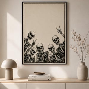 May include: A framed wall art print featuring a black and white illustration of five skeletons posing together. The skeletons are arranged at the bottom of the frame, making various hand gestures including peace signs and a rock and roll hand sign.