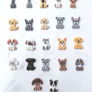 Twenty-two colorful clay dog breed cutouts in various colors arranged on a white marble surface showing each unique breed design.