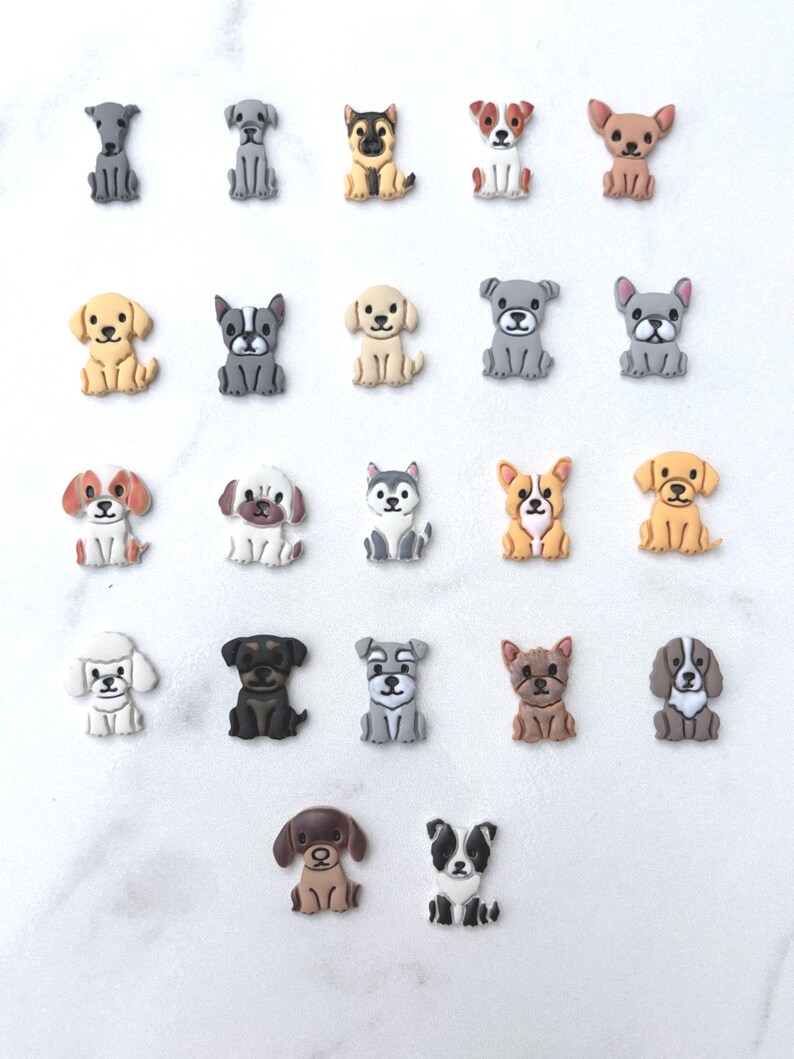 Twenty-two colorful clay dog breed cutouts in various colors arranged on a white marble surface showing each unique breed design.