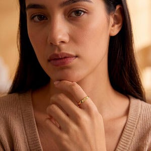 Puede incluir: Un anillo de oro con el nombre "Sophia" grabado. El anillo se lleva en un dedo. El anillo es una banda simple con una placa rectangular con el nombre. El anillo es de color oro brillante.