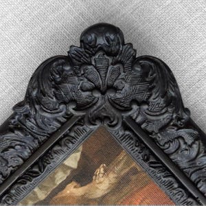 Close up of black frame featuring elaborate floral detailing.