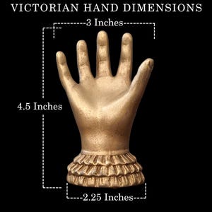 K&ouml;nnte beinhalten: Eine goldfarbene viktorianische Handskulptur, 11,4 cm hoch und 7,6 cm breit, mit ger&uuml;schtem Sockel. Der Text "VICTORIAN HAND DIMENSIONS" steht oben, mit Ma&szlig;en in Zoll.
