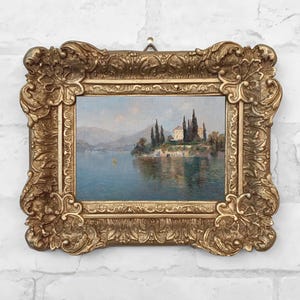 Framed vintage-style canvas print of a serene landscape painting by Emilie Mediz-Pelikan, showing Villa Cipressi overlooking Lake Como, with tall cypress trees, terraced stone walls, and still blue water, all set in an ornate gold antique-style frame.