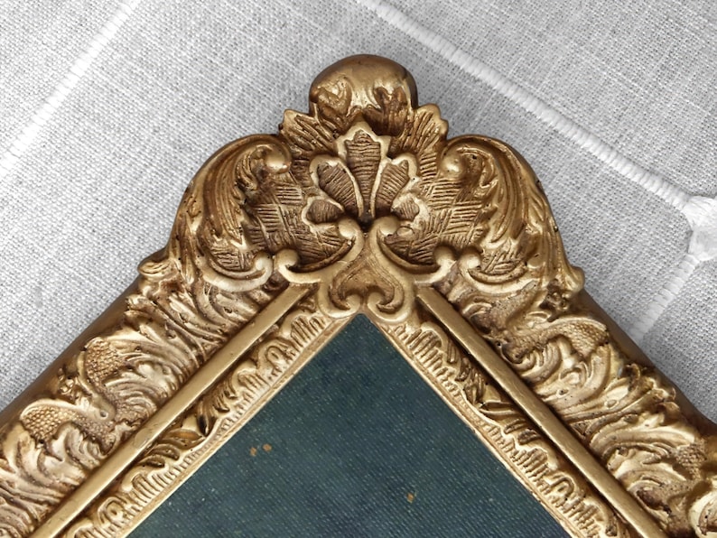 Close up of gold toned frame featuring elaborate floral detailing.