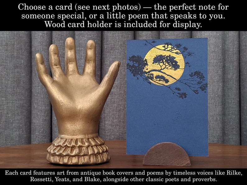 K&ouml;nnte beinhalten: Ein goldfarbener kartenhalter in Handform mit ger&uuml;schtem Sockel, der eine blaue Karte mit einem goldenen Mond- und Baumdesign h&auml;lt. Der Text lautet: "W&auml;hlen Sie eine Karte...Kartenhalter aus Holz ist im Lieferumfang enthalten."