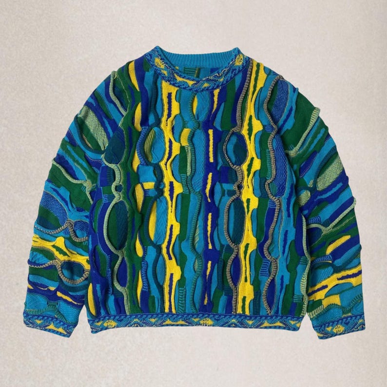 May include: A vibrant patterned jumper in blue, green, and yellow. The jumper has a distinctive textured design with raised details and a ribbed neckline and cuffs. The style is reminiscent of vintage knitwear.