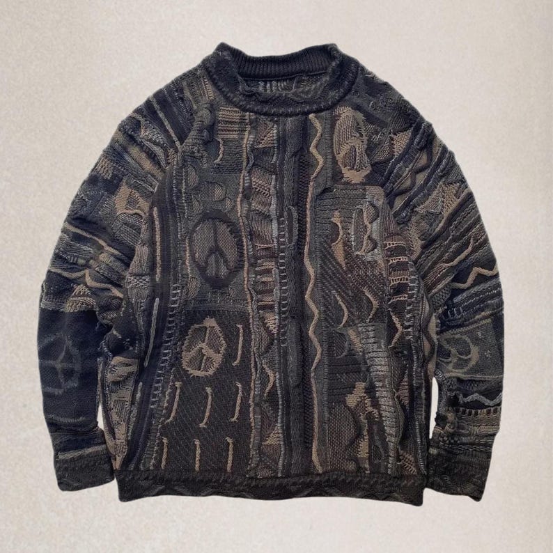 May include: An oversized sweater in black, brown, and grey with a high neckline. The textured knitwear features geometric and peace sign patterns. The garment has a vintage aesthetic and is suitable for cooler weather.