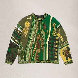 May include: A green, brown, and yellow crew neck sweater. The garment displays a variety of patterns and images, including a lion, geometric shapes, and abstract designs. The sleeves are long and the overall style is oversized.