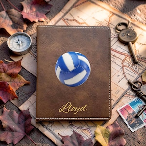 May include: A brown rectangular passport holder featuring a blue and white volleyball graphic centered on the front cover. The name Lloyd is printed in gold cursive script below the ball. The cover has visible white stitching along the edges.