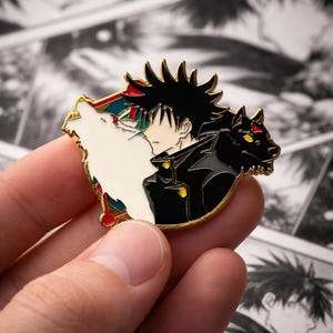 May include: An enamel pin with a gold border, depicting a character from an anime series. The pin features a character with black hair and a black jacket, alongside a white wolf and a black wolf.