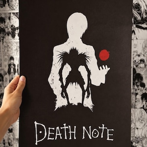 May include: A black rectangular poster featuring a white silhouette of a person standing behind a black, spiky, creature-like figure. A small red apple is positioned near the creature. The text "DEATH NOTE" is printed in white at the bottom.