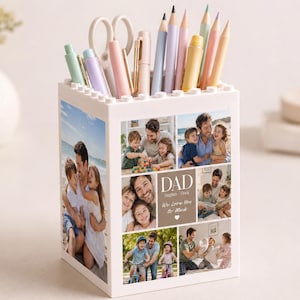 May include: A white pen holder with a collage of family photos. The pen holder is filled with pens, pencils, and scissors. The collage includes the word "DAD" and the phrase "We Love You So Much."