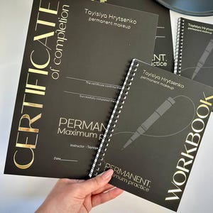 May include: Black certificate of completion with gold lettering, featuring the text "CERTIFICATE of completion" and "PERMANENT Maximum practice". A spiral-bound workbook and a black tray are also visible. The certificate confirms successful completion of a permanent makeup course.