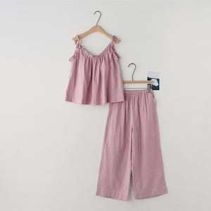 May include: A two-piece pajama set in a soft mauve color. The set includes a camisole top with tie straps and wide-leg pants. Both pieces are hanging on wooden hangers against a plain white background.