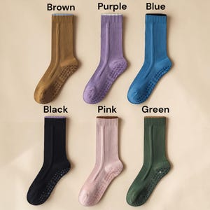 May include: Six pairs of socks in various colors: brown, purple, blue, black, pink, and green. Each sock has a ribbed design and a non-slip grip on the sole. The socks are displayed on a neutral background.