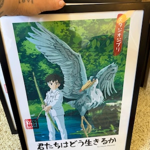 Puede incluir: Impresi&oacute;n art&iacute;stica enmarcada que presenta a un ni&ntilde;o con un traje blanco y una garza. La garza tiene plumas grises y blancas. El fondo muestra un exuberante bosque verde. Incluye texto japon&eacute;s y la fecha 06.14.2023.