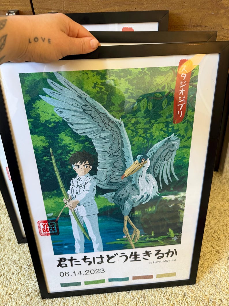 Puede incluir: Impresi&oacute;n art&iacute;stica enmarcada que presenta a un ni&ntilde;o con un traje blanco y una garza. La garza tiene plumas grises y blancas. El fondo muestra un exuberante bosque verde. Incluye texto japon&eacute;s y la fecha 06.14.2023.