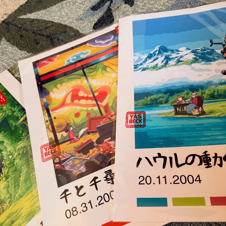 Op de afbeelding: Verschillende kleurrijke posters met Japanse animatiekunst. E&eacute;n poster heeft een rode stempel met "YAS BECK DESIGN". De posters bevatten Japanse tekst en data. De kunstwerken tonen sc&egrave;nes met personages en landschappen.