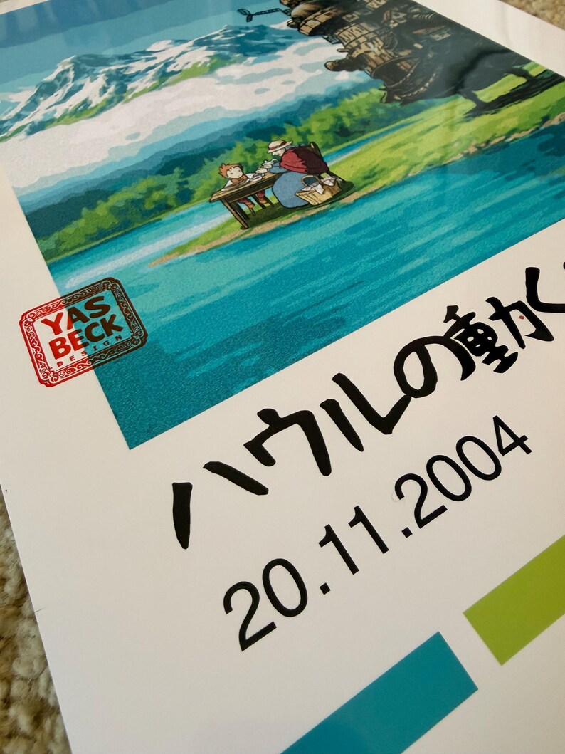 Op de afbeelding: Een poster met een sc&egrave;ne uit een animatiefilm, met een bergketen, water en een mechanische structuur op de achtergrond. Japanse tekst en de datum 20.11.2004 zijn ook zichtbaar.
