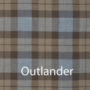 Puede incluir: Primer plano de una tela a cuadros en tonos marrón, gris y azul claro. La palabra "Outlander" está impresa en blanco en la parte inferior de la tela. El patrón es un diseño tartán clásico.