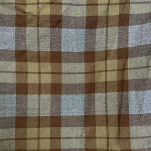 Puede incluir: Una tela tejida que presenta un patrón de cuadros clásico con líneas que se cruzan en tonos marrón oscuro, verde oliva apagado y gris claro. El textil muestra un diseño de cuadrícula consistente con una textura de tejido visible.