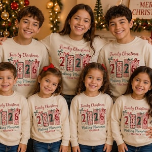 May include: A group of seven people wearing matching cream-colored crewneck sweatshirts. Each sweatshirt features a graphic print with the text Family Christmas, the year 2026, and the phrase Making Memories TOGETHER in red and green colors.