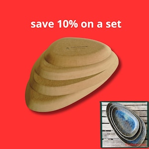 Op de afbeelding: Een stapel van drie ovale keramische borden met een getextureerde, blauwe en bruine glazuurafwerking. De tekst "save 10% on a set" staat boven de borden. De onderkant van het bovenste bord is beige met kleine, donkere tekst.