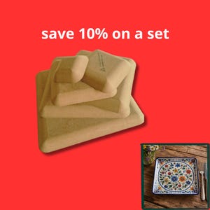 Puede incluir: Una pila de cuatro bandejas cuadradas de madera sin terminar, de color marrón claro, con esquinas redondeadas y bordes elevados. El texto "save 10% on a set" aparece sobre la pila. Un recuadro muestra un plato cuadrado con diseño floral.