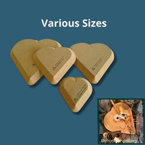 May include: Four heart-shaped wooden forms in various sizes arranged on a blue background. Each form features a light brown finish and a small logo stamp. An inset image shows a finished heart-shaped ceramic dish decorated with dried flowers.