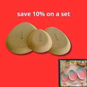 May include: Three tan ceramic dishes with rounded, pebble-like shapes shown from the underside, featuring the text 'Pottery Forming Europe' and a logo. The text 'save 10% on a set' appears above. A small inset shows the pink and blue tops.