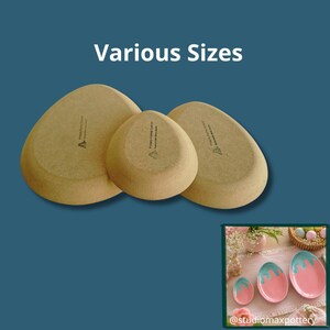 Può includere: Tre piatti in ceramica ovali e testurizzati color beige, mostrati dal lato inferiore, ognuno con un piccolo logo stampato. Il testo 'Various Sizes' appare sopra. Un'immagine inserita mostra tre piatti a forma di uovo rosa e turchese.