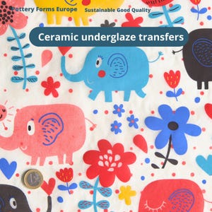 May include: Ceramic underglaze transfers featuring a repeating pattern of colourful elephants, flowers, and hearts on a white background. The text Pottery Forms Europe Sustainable Good Quality and Ceramic underglaze transfers are visible. A 1 euro coin is present.