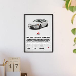 Puede incluir: Impresión enmarcada que presenta un coche Mitsubishi Lancer Evolution blanco. La impresión incluye el logotipo de Mitsubishi y el texto: "THE ULTIMATE EVOLUTION OF RALLY HERITAGE". También enumera la potencia del coche en 286 CV y la velocidad máxima en 250 km/h.