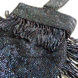 May include: A black beaded bag with a fringe detail. The beads have a slight iridescent sheen.