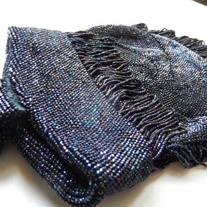 May include: A vintage beaded purse with a dark blue iridescent finish and a fringe detail.