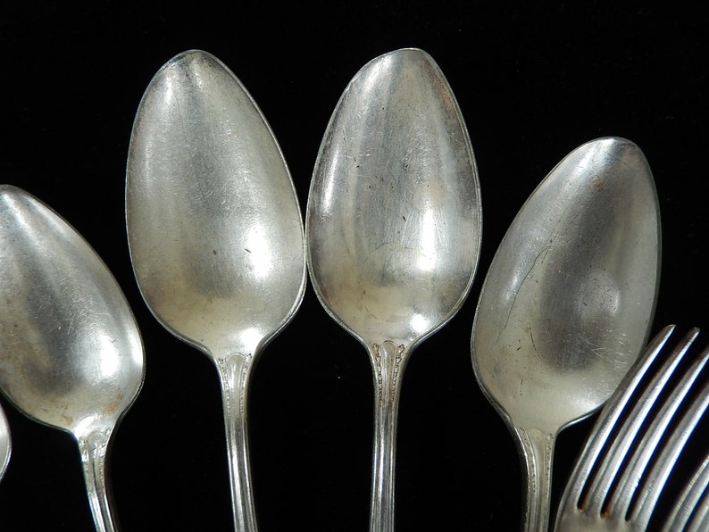 K&ouml;nnte beinhalten: Ein Set aus f&uuml;nf silbernen L&ouml;ffeln und einer silbernen Gabel. Die L&ouml;ffel sind alle gleich gro&szlig; und haben eine abgerundete Schale. Die Gabel hat vier Zinken.