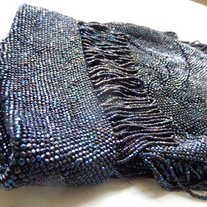 May include: A vintage beaded evening bag with a fringe detail. The bag is made of iridescent blue beads and has a rectangular shape.