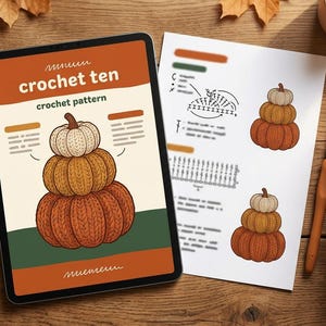 Peut inclure: Une tablette numérique affichant un modèle de crochet intitulé crochet ten avec une illustration de trois citrouilles empilées, une fiche d'instructions imprimée avec des schémas, un crochet en bois et une pelote de laine orange.
