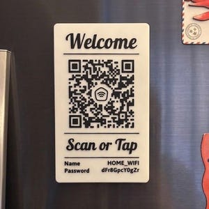May include: A collection of refrigerator magnets. A white magnet with the word "Welcome" and a QR code is displayed. Other magnets include a red airplane, a strip of bacon, and a pair of mushrooms with red caps and white spots.