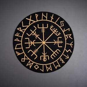 May include: A circular black patch featuring an embroidered gold Vegvisir symbol at the center, surrounded by a ring of gold runic characters. The design is symmetrical with eight distinct staves radiating from the middle point.