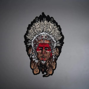 May include: A detailed embroidered patch featuring a portrait of a person wearing a large, elaborate feathered headdress. The design uses a colour palette of red, white, black, and tan, with intricate line work defining the facial features and feathers.