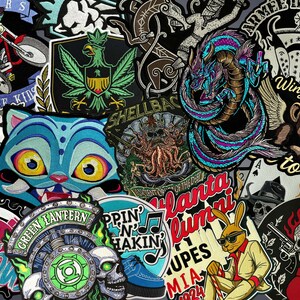 May include: A collection of embroidered patches featuring diverse designs including a blue cat face, a green dragon, a skull with a Green Lantern logo, a rabbit in a suit, a winged monkey, and various text-based emblems like Bikers for the Kids.