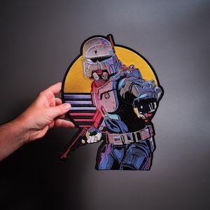 May include: An embroidered patch featuring a futuristic armored character in a helmet, pointing forward while holding a blaster. The design includes a circular background with a yellow sun and horizontal stripes in shades of purple, blue, and pink.