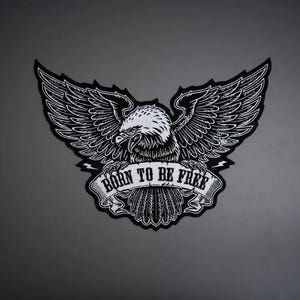 May include: A black and white embroidered patch featuring a detailed illustration of a bald eagle with wings spread wide. The eagle is clutching a banner that displays the text BORN TO BE FREE in bold, capitalized, black lettering.