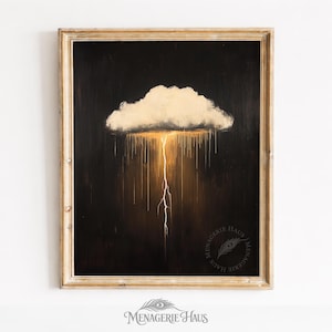 May include: A framed artwork depicts a cloud with a golden glow and a lightning bolt against a dark background. The artwork is in a gold-colored frame. The image has the text "Menagerie Haus".