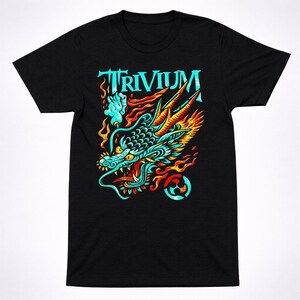 May include: Black t-shirt featuring a vibrant dragon head design with teal, orange, and yellow accents. The word "TRIVIUM" is displayed in teal above the dragon. The dragon design includes flames and a circular symbol.